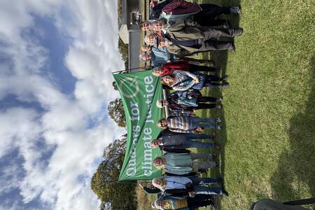 Quakers in Scotland standing under Quakers for climate justice green banner, outside the Scottish Parliament