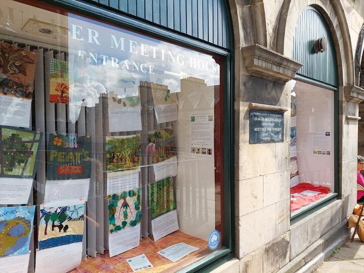 Quaker Meeting House window with sewn banners and explanations about the panels in the windows.