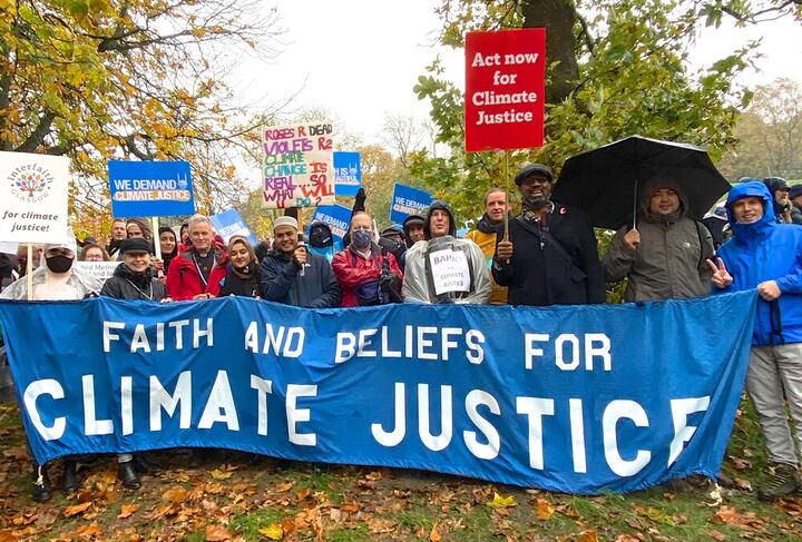 Faith and Beliefs for Climate Justice Pictures of various faith leaders standing in the rain holding a banner that says Faith and Beliefs for Climate Justice