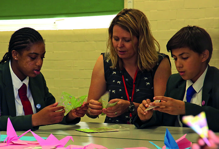 Young people learn about peace at a London school. Image: Di Tatham for Quakers in Britain Two children and an adult woman make peace cranes.