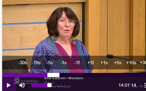 Sila at Parliament A woman stands before a microphone at the Scottish Parliament, delivering a speech